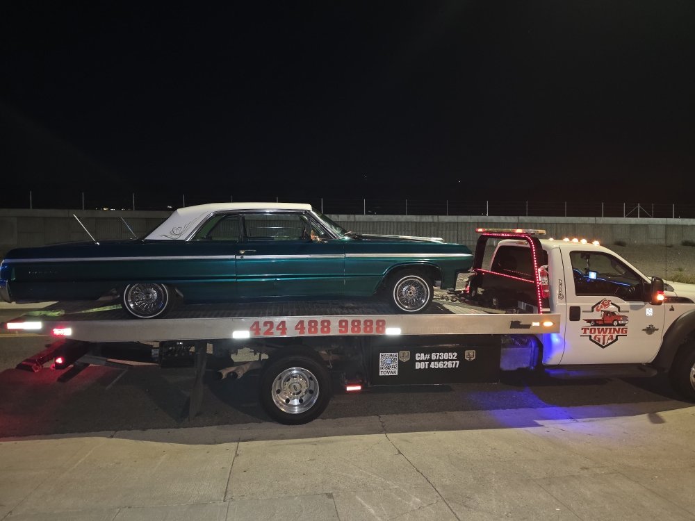 Towing GTA flatbed transporting a classic car at night